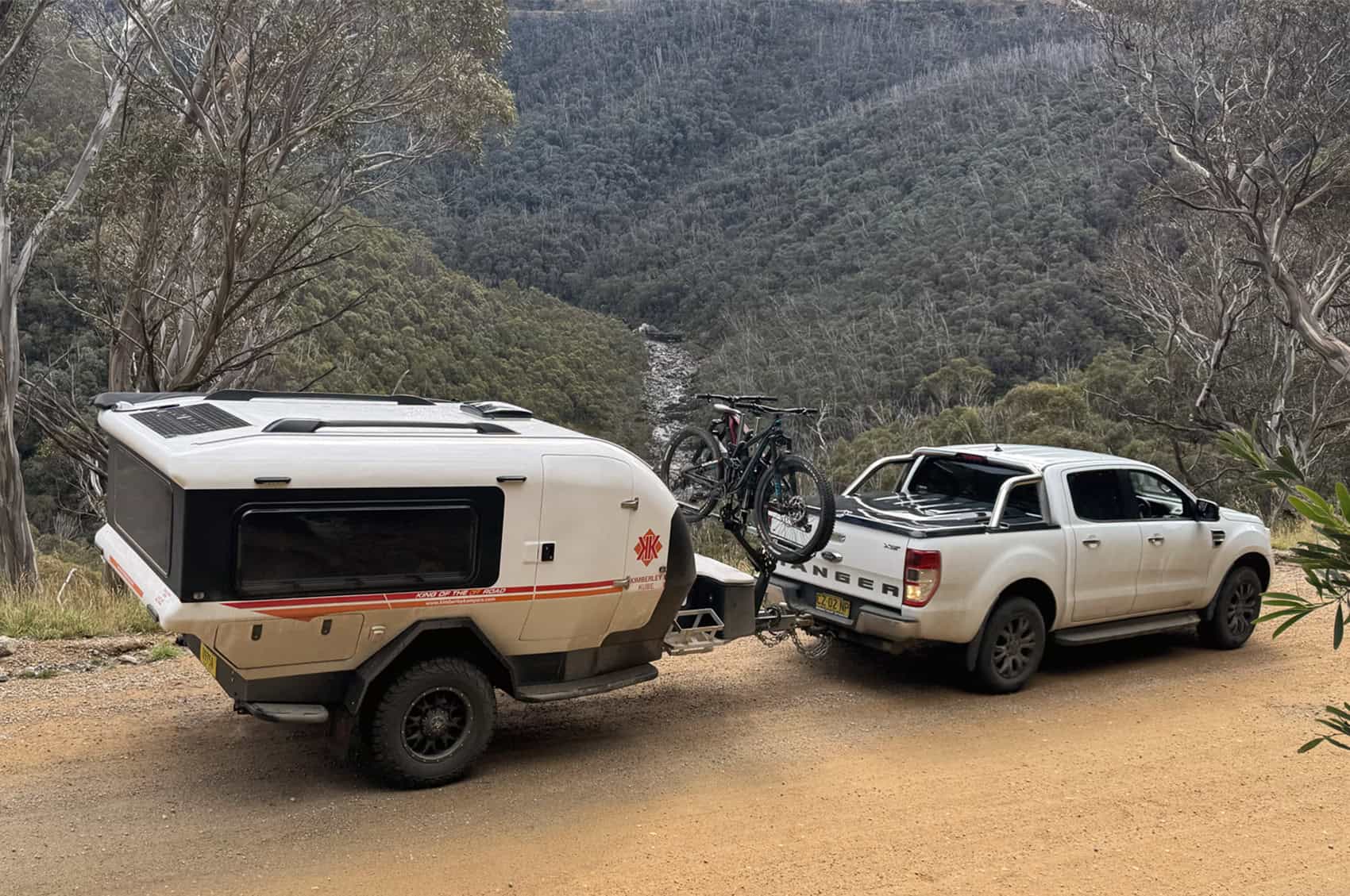 A Kimberley Kube teardrop camper trailer parked on a remote dirt road, surrounded by dry grass and distant trees, highlighting its off road capability.