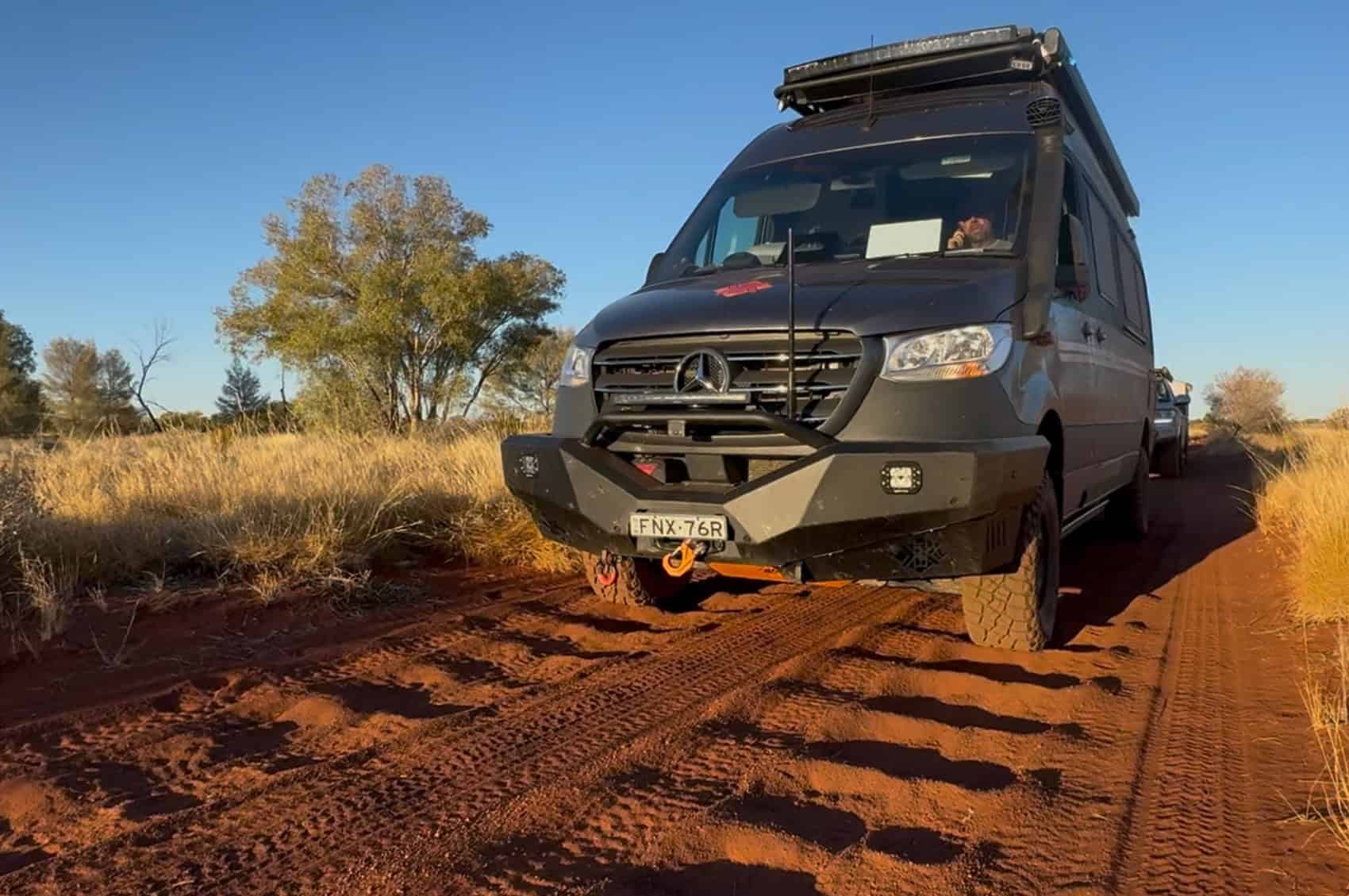 Kruiswagen off-road motorhome navigating an Australian desert track, surrounded by arid terrain and sparse vegetation.
