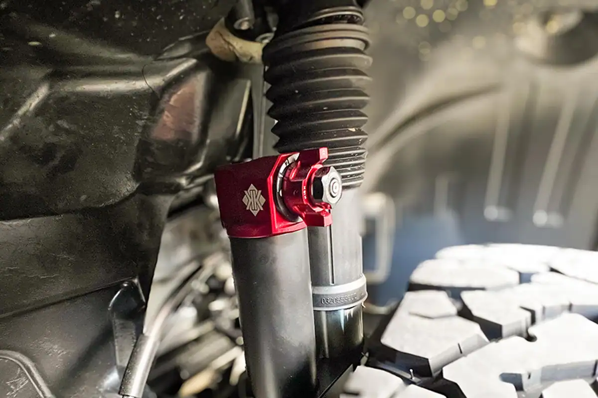 Close-up of Kimberley Kampers offroad motorhome adjustable suspension system, showing the red anodised height-adjustable shock absorber top.
