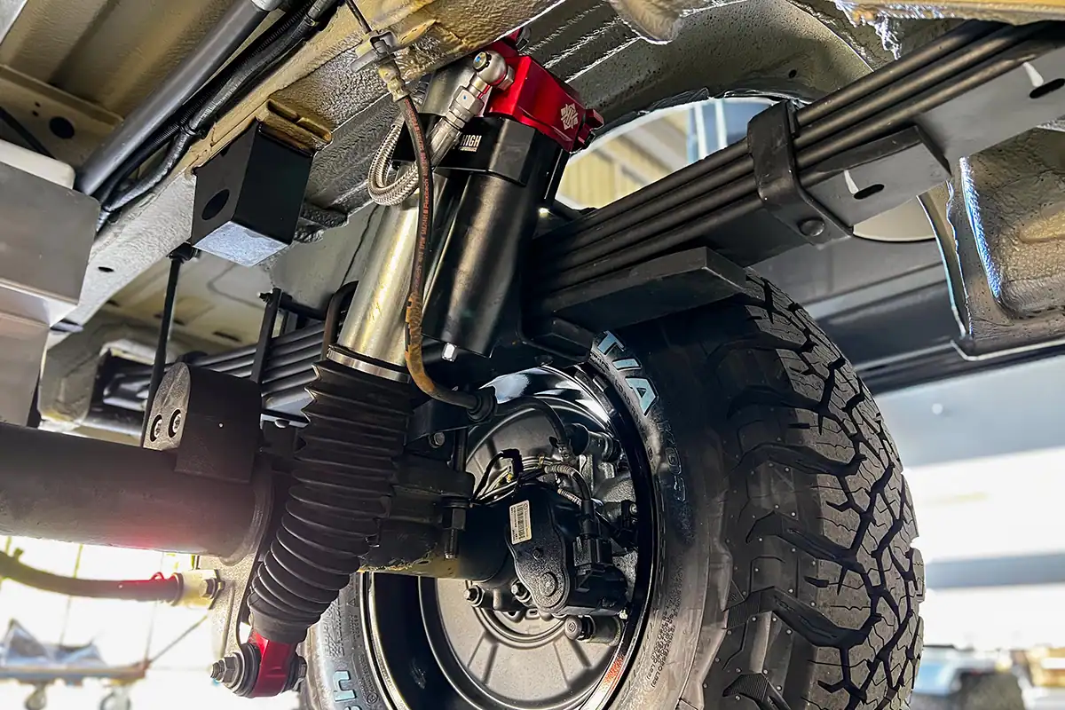 Close-up of Kimberley Kampers off-road motorhome suspension with heavy-duty shock absorber and rugged tire, designed for durability and performance in remote Australian terrains.